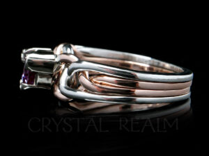 Side view of a triangle-cut, lab-created alexandrite on a platinum and 14K rose gold engagement puzzle ring